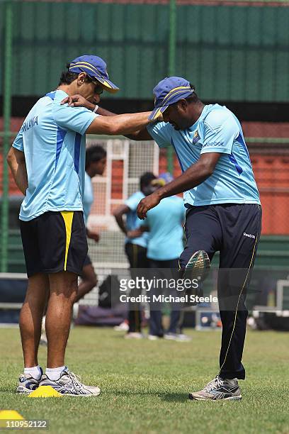 Muttiah Muralitharan of Sri Lanka stretches aided by physio Tommy Simisek during the Sri Lanka nets session at the R. Premadasa Stadium on March 28,...