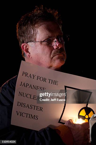 Demonstrators hold candles and signs at the 32nd annual vigil in remembrance of the disaster at the Three Mile Island Nuclear Plant March 28, 2011 in...