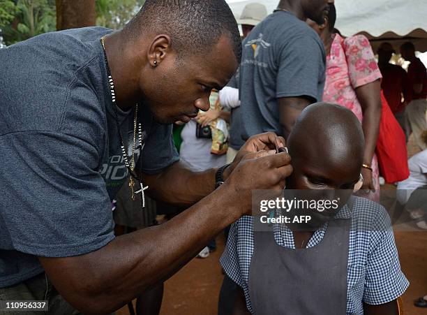 This picture taken on March 20, 2011 shows Minnesota Vikings Running Back, Adrian Peterson as he adjusts a Starkey hearing aid for a young girl in...