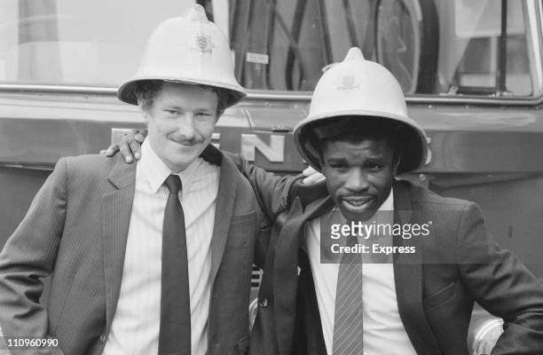 British light welterweight boxers Terry Marsh and Clinton McKenzie wearing firemen's helmets, 17th August 1984. Marsh is a former firefighter.