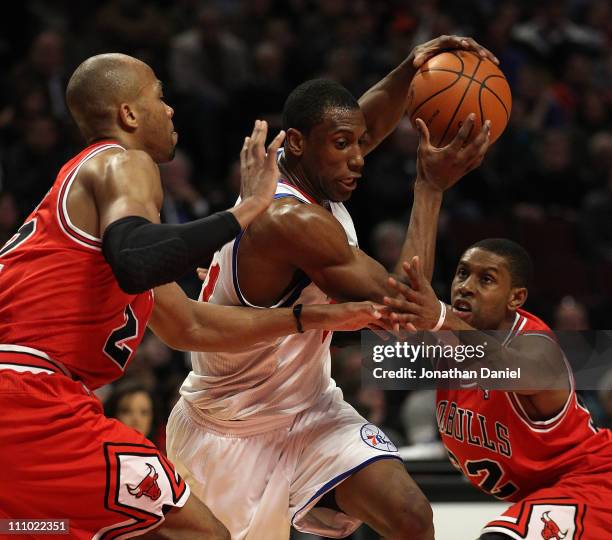 Thaddeus Young of the Philadelphia 76ers drives between Taj Gibson and C.J. Watson of the Chicago Bulls at the United Center on March 28, 2011 in...