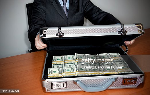 Man holding silver briefcase full of $100 bills Man holding silver briefcase full of $100 bills