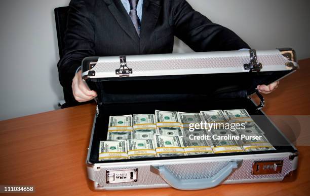 man holding silver briefcase full of $100 bills - 汚職 ストックフォトと画像