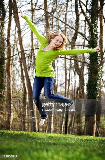 happy girl jumping in air - first day of spring stock-fotos und bilder