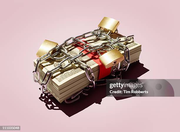 stack of $100 notes in chains and padlocks. - asset protection stock pictures, royalty-free photos & images