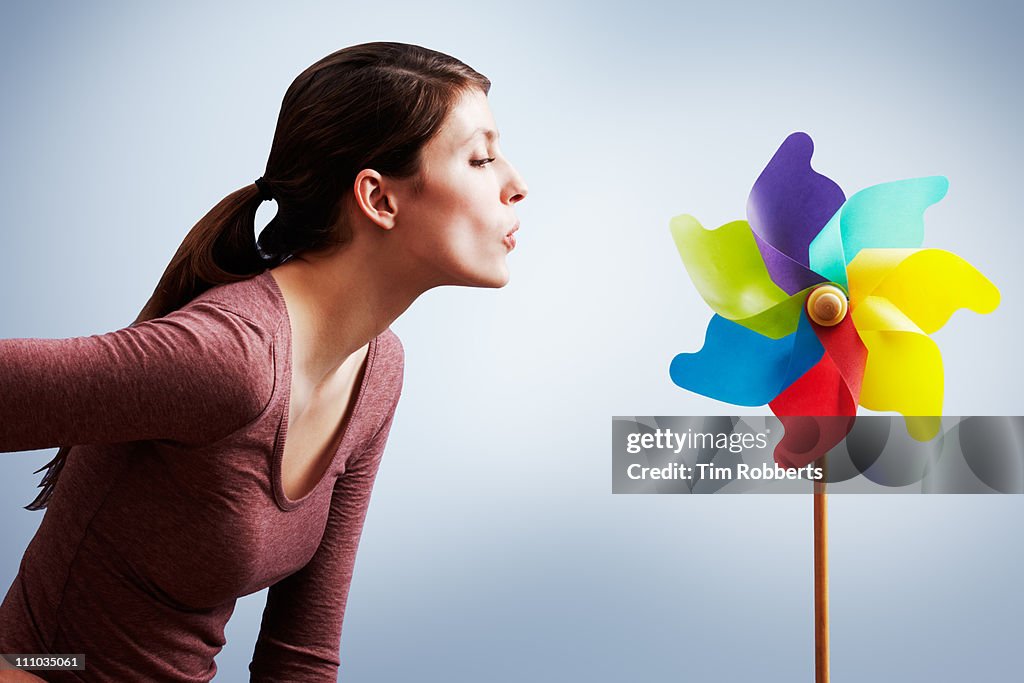 Young woman blowing pin wheel