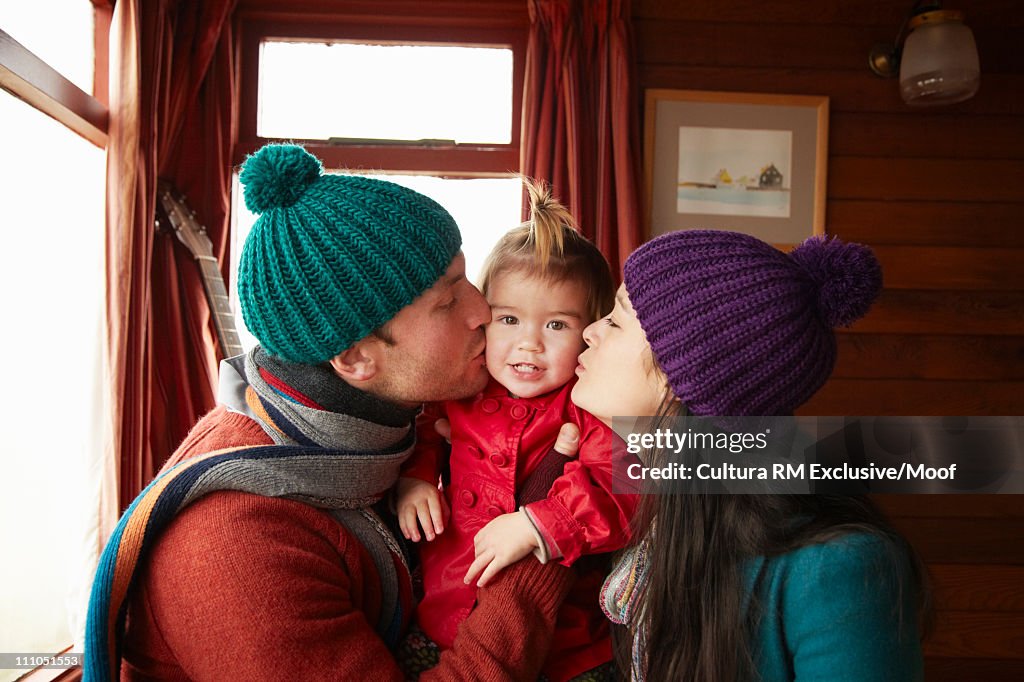 Parents kissing daughter in beach hut