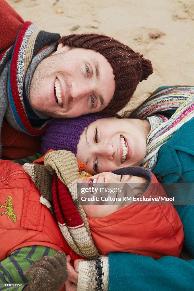 Family lying on a sandy beach in winter