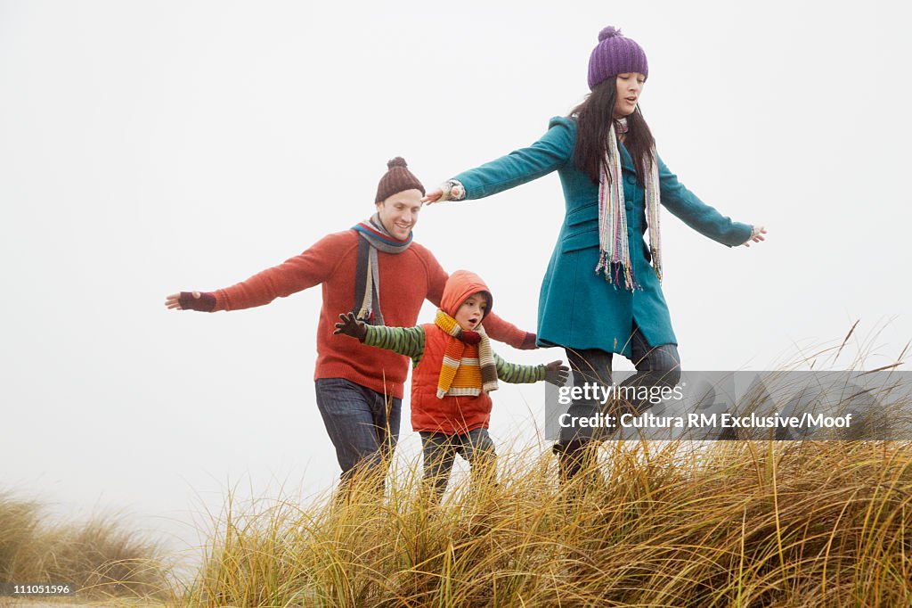 Family walking on dunes with arms out