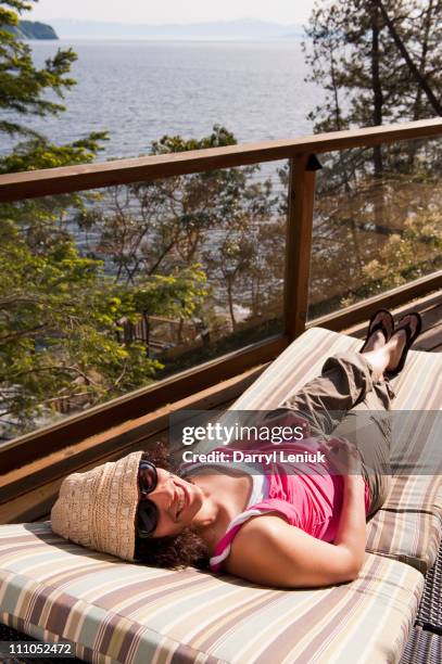 hispanic woman laying on deck chair sunbathing - terrace british columbia stock pictures, royalty-free photos & images