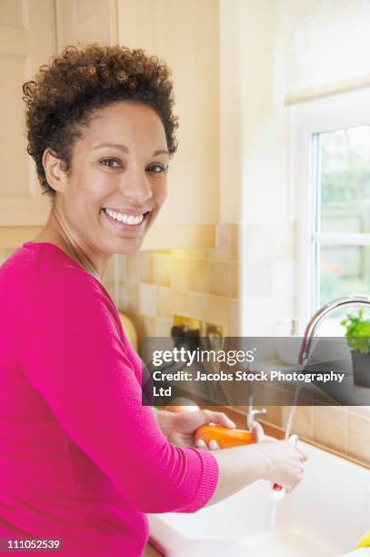 mixed race woman washing dishes in sink - women with health faucet stock pictures, royalty-free photos & images