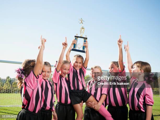 cheering girl soccer players posing with trophy - child trophy stock-fotos und bilder