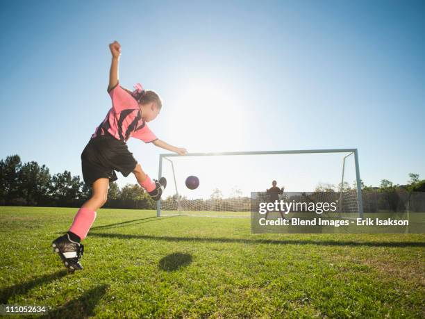 girl soccer player kicking soccer ball at net - girls playing soccer stock pictures, royalty-free photos & images