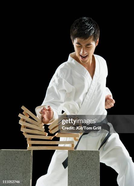 asian male karate black belt breaking wooden planks - zwarte band stockfoto's en -beelden