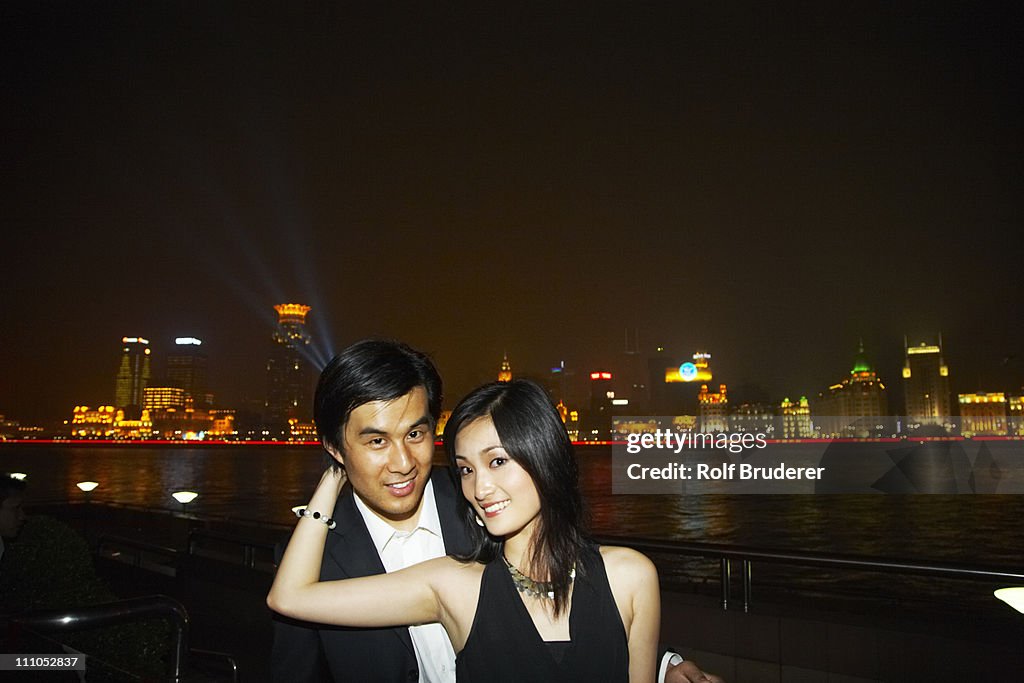 Chinese couple hugging on city waterfront