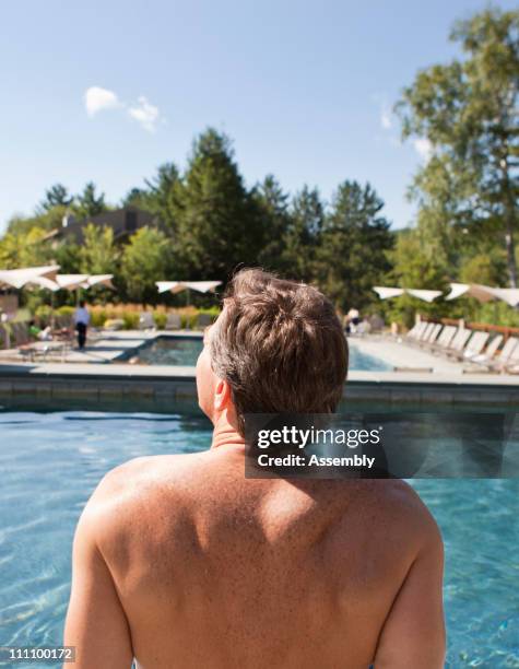 mature man relaxing next to a resort pool - auf rücken liegen stock-fotos und bilder
