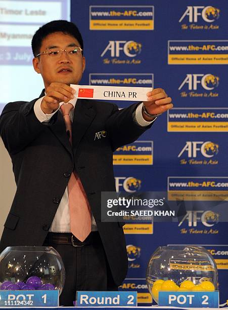 An Asian Football Confederation official displays a draw for China during the official draw for the Asian qualifier round 1 and round 2 of the 2014...