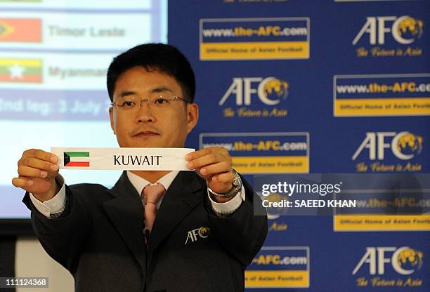 An Asian Football Confederation official displays a draw for Kuwait during the official draw for the Asian qualifier round 1 and round 2 of the 2014...