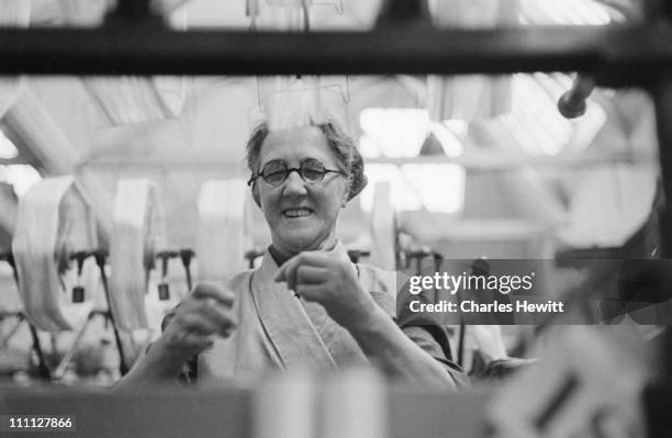 Bella Adamson, a winder at the Wintherthur factory in Dunfermline, Scotland, helps to weave Chinese silk for the wedding dress of Princess Elizabeth...