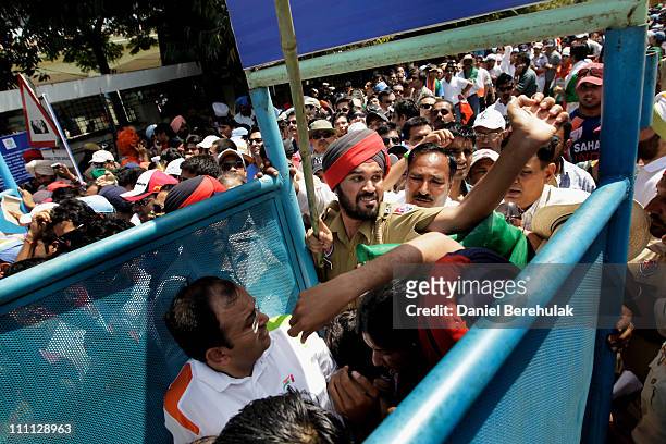 Indian security personnel try to control spectators prior to passing through a metal race for security screening prior to the start of the 2011 ICC...