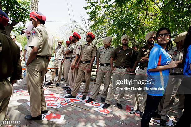 Indian security personnel stand guard as spectators queue prior to passing through a metal race for security screening prior to the start of the 2011...