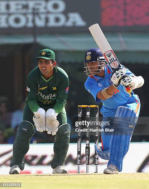 Sachin Tendulkar of India drives with Kamran Akmal of Pakistan looking on during the 2011 ICC World Cup second Semi-Final between Pakistan and India...