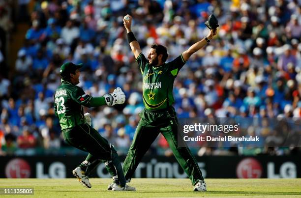 Captain Shahid Afridi of Pakistan celebrates with team mate Kamran Akmal after taking the catch to dismiss Sachin Tendulkar of India off the bowling...