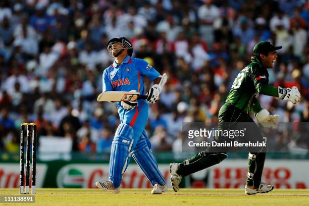 Sachin Tendulkar of India looks skywards as Kamran Akmal runs to congratulate Shahid Afridi of Pakistan who took the catch off the bowling of Saeed...