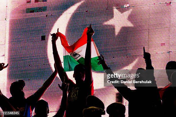 Cricket fans hold an Indian flag as the flag of Pakistan is displayed on an electronic scoreboard during the 2011 ICC World Cup second Semi-Final...