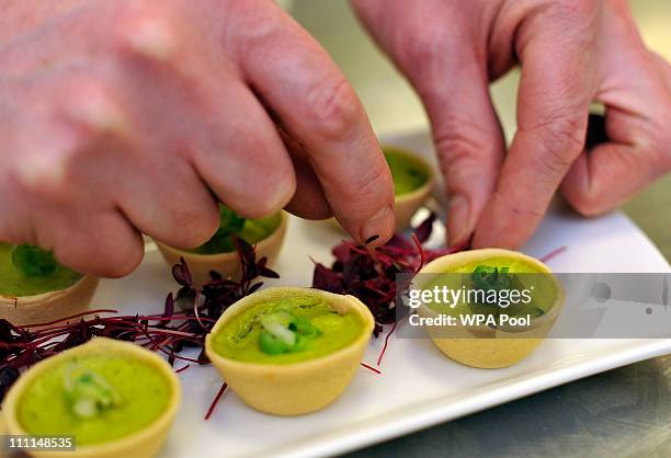 Royal chef adds the finishing garnish to a platter of Wilted Spring Onion and Water Cress quiche canapes, food akin to that which is usually served...