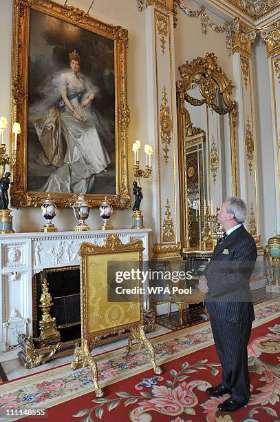 Edward Griffiths, Deputy Master of the Household looks at a painting of Queen Alexandra, wife of Edward VII, by Francois Flameng, in the White...