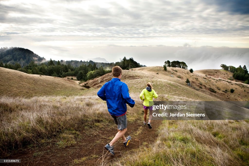 A man and woman trail running.