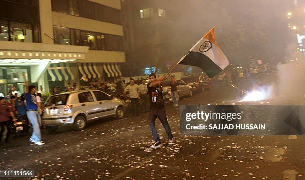 An Indian fan holds a national flag as he celebrates India's victory in a semi-final of the Cricket World Cup 2011 match against Pakistan, in Mumbai...