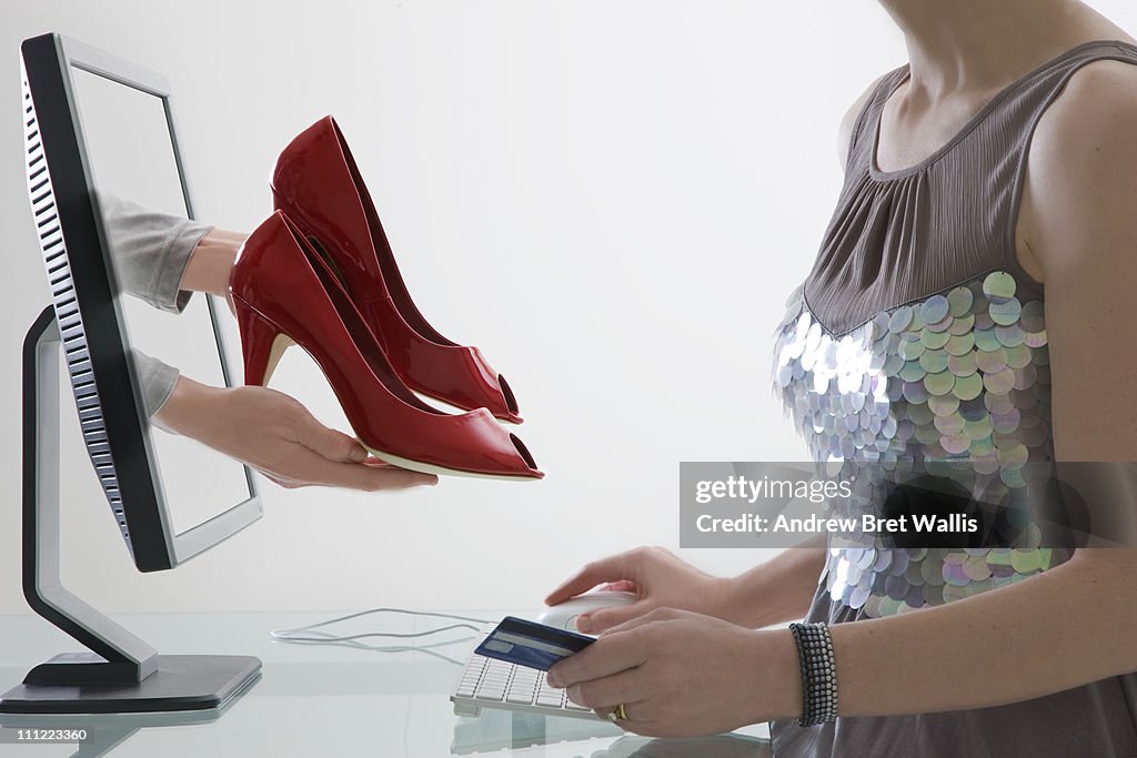 Woman choosing and paying for shoes via computer
