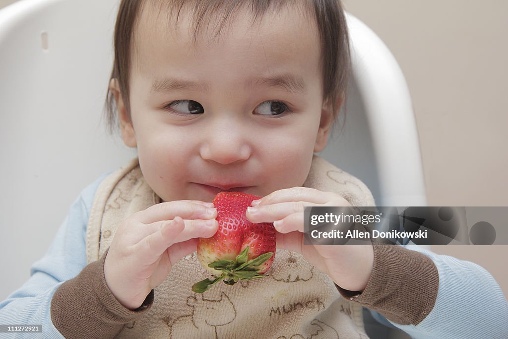 Smirking boy holding strawberry