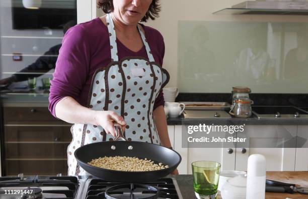 Female Cook Dry Frying Pine Nuts In Pan High-Res Stock Photo