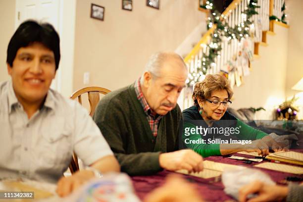 family plays lotteria a mexican bingo game - family game night stock-fotos und bilder