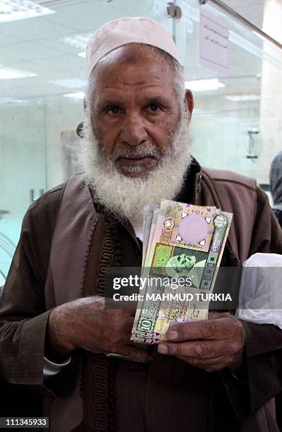 Libyan man holds outdated bank notes, which had been removed from circulation several years ago and reissued recently by the central bank due to cash...