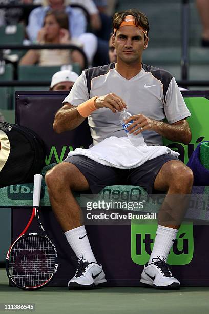 Roger Federer of Switzerland has a drink of water as he sits on the bench during a change over against Rafael Nadal of Spain during their men's...