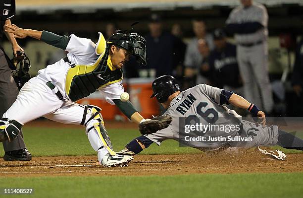 Brendan Ryan of the Seattle Mariners slides into home safely past Kurt Suzuki of the Oakland Athletics during the sixth inning at the Oakland-Alameda...