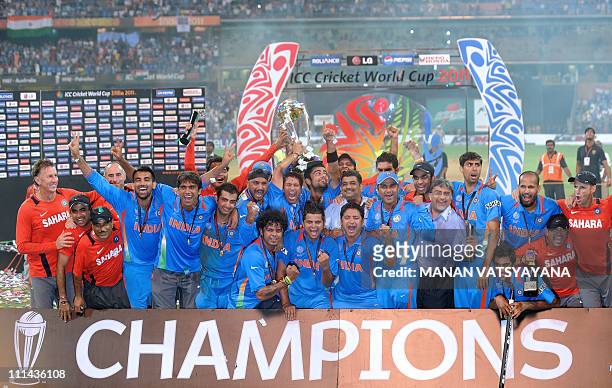 Indian cricketers pose with the trophy as they celebrate after beating Sri Lanka in the ICC Cricket World Cup 2011 final match at The Wankhede...