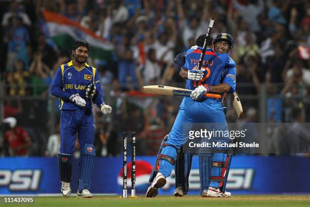 Dhoni of India celebrates with Yuvraj Singh after hitting a six to win by six wickets as Kumar Sangakkara captain of Sri Lanka looks on during the...