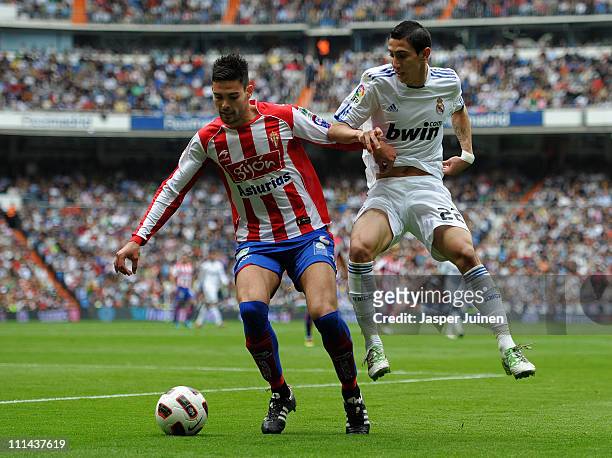 Angel Di Maria of Real Madrid duels for the ball with Alberto Botia of Sporting Gijon during the la Liga match between Real Madrid and Sporting Gijon...