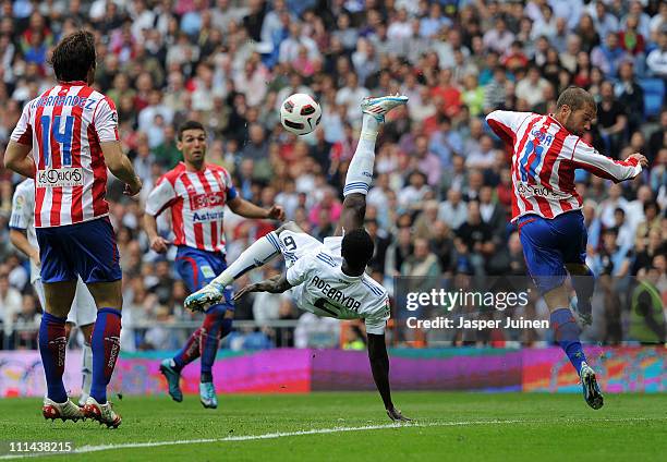 Emmanuel Adebayor of Real Madrid uses an overhead kick to shoot on goal past Alberto Lora of Sporting Gijon during the la Liga match between Real...