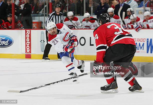 Brian Gionta of the Montreal Canadiens fires a shot while being defended by Mark Fayne of the New Jersey Devils during the game at the Prudential...