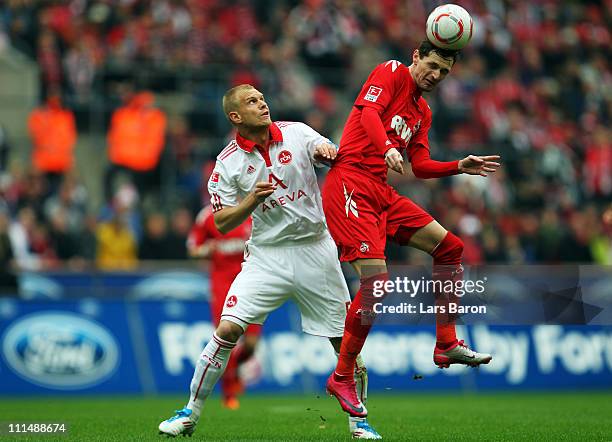 Andreas Wolf of Nuernberg challenges Milivoje Novakovic of Koeln during the Bundesliga match between 1. FC Koeln and 1. FC Nuernberg at...