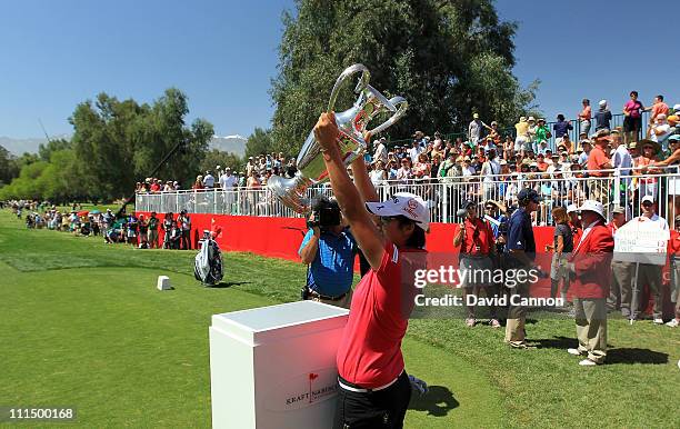 Yani Tseng of Taiwan plays walks onto the 1st tee and raises the trophy she won last year at the start of her final round in the 2011 Kraft Nabisco...