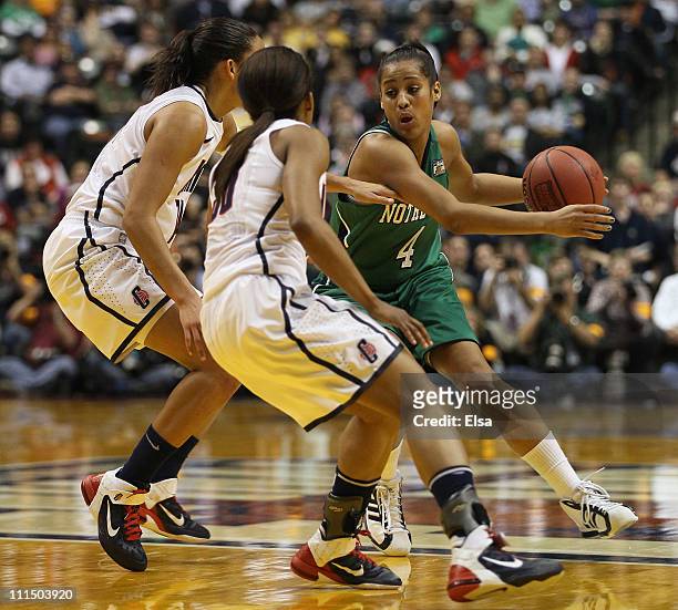 Skylar Diggins of the Notre Dame Fighting Irish tries to get around Kelly Faris and Lorin Dixon of the Connecticut Huskies during the semifinals of...
