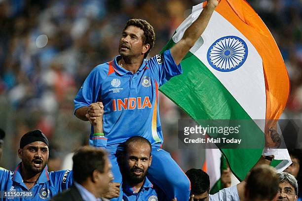 Indian cricketer Sachin Tendulkar waves the Indian Tricolour celebrating their team's victory during the ICC Cricket World Cup final match between...