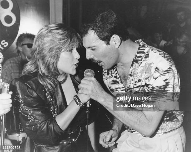 Singer Freddie Mercury of Queen performs a duet with Samantha Fox during a party at Kensington Roof Gardens in London, 12th July 1986. The event is...